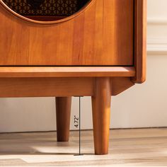 a close up of a clock on top of a wooden table with measurements in front of it