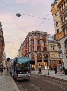 a bus is driving down the street in front of some buildings and people walking on the sidewalk