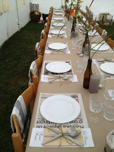 a long table is set up with plates and napkins for an outdoor dinner party