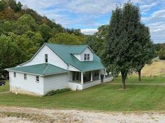 a white house sitting on top of a lush green field next to a dirt road