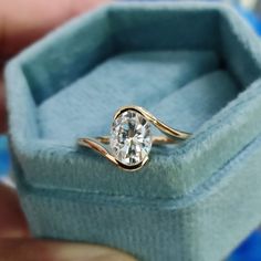 a close up of a person's hand holding an engagement ring in a box