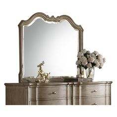 a dresser with flowers and a mirror on it