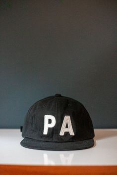 PA felt letters stitched on brushed cotton twill.  Fabric strap with an adjustable snap.  Flat brim hat. Unstructured 6-Panel.   Colors: Black, Navy, Olive, and Rust Free Shipping in the USA! One Size fits most. Flat Brim Cotton Hat With Letter Patch, Cotton Flat Brim Hat With Letter Patch, Cotton Snapback Hat With Letter Embroidery And Flat Bill, Cotton Snapback Hat With Letter Embroidery, Everyday Six-panel Hat With Logo Patch, Adjustable Six-panel Baseball Cap With Letter Print, Adjustable Six-panel Dad Hat With Letter Print, Black Cotton Hat With Letter Patch, Adjustable Six-panel Snapback Hat With Letter Patch