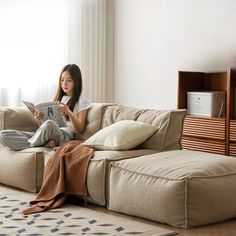 a woman sitting on a couch reading a book