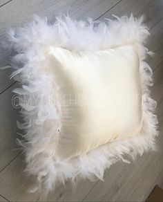 a white feather pillow on a wooden floor