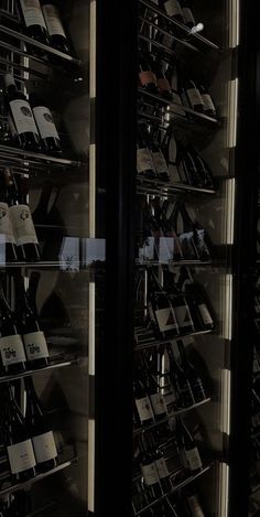 there are many wine bottles in the glass case on this display shelf, and one is empty