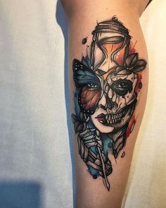 a woman's leg with a skull and butterfly tattoo on her thigh, which is covered in watercolor paint