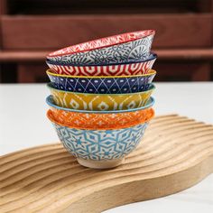 five bowls stacked on top of each other in front of a wooden tray with a white background