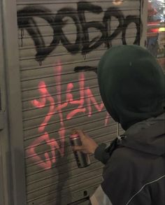 a man spray painting graffiti on the side of a garage door that has been closed