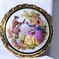 an ornately decorated broochle with a man and woman in the woods on it