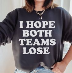 a woman wearing a black sweatshirt that says, i hope both teams lose on it