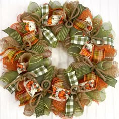 a wreath made out of mesh and fabric with pumpkins on the front, sitting on a white door