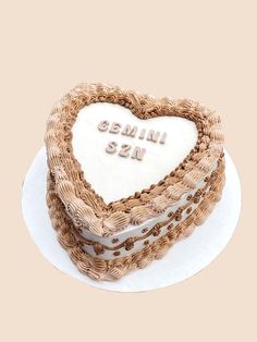 a heart - shaped cake with the words canni san written on it sits on a plate