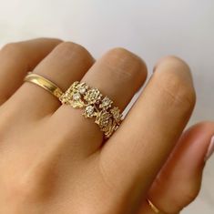 a woman's hand wearing a gold ring with flowers on the middle and sides