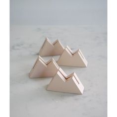 three pieces of pink metal sitting on top of a white marble countertop next to each other