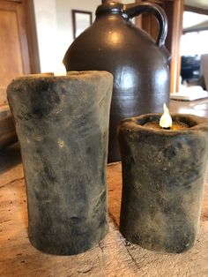 two candles sitting on top of a wooden table next to a tea pot and kettle