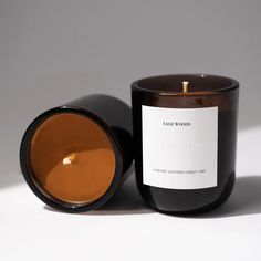 a candle with a label on it sitting in front of a white background and gray backdrop