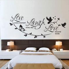 a bed room with a neatly made bed and a wall mounted quote on the wall