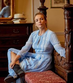 a woman sitting on top of a wooden bench next to a dresser and mirror in a room