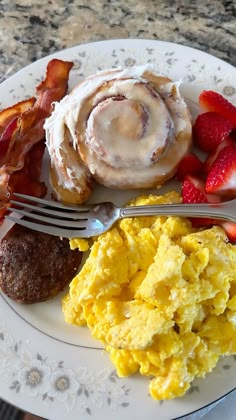 an english muffin, bacon, and scrambled eggs on a plate with a fork