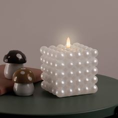 a lit candle sitting on top of a table next to a mushroom figurine