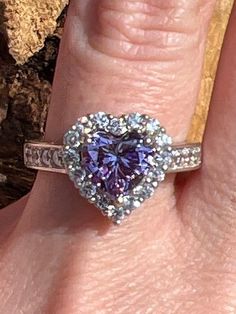 The purple cubic zirconia in this ring has a measurement of approx. 7.8mm x 7.5mm. The other cubic zirconias in this ring have a measurement of approx. 1.9mm. The back of shank has a measurement of approx. 3.4mm. This ring weighs approx. 4.7 grams. Size: 8 US. Stock number: 257 Heart Cut Cubic Zirconia Ring With Halo Setting, Dazzling Amethyst Diamond Ring For Anniversary, Dazzling Purple Rings With Prong Setting, Dazzling Purple Ring With Prong Setting, Cubic Zirconia Heart Ring With Brilliant Cut For Promise, Cubic Zirconia Heart Ring With Center Stone, Heart-shaped Cubic Zirconia Ring With Prong Setting, Heart Shaped Cubic Zirconia Ring With Prong Setting, Heart Cut Cubic Zirconia Jewelry With Center Stone