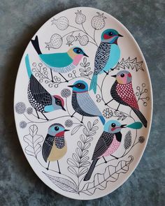 a plate with birds painted on it sitting on top of a gray tablecloth covered floor