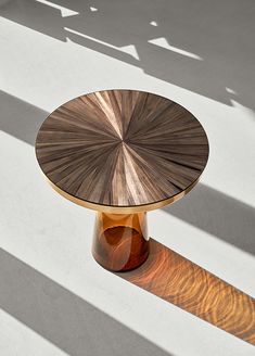 a wooden table sitting on top of a white floor next to a shadow cast wall