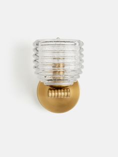 a glass and brass wall light on a white background with a gold finish, it is also available in the bathroom or bedroom