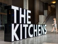 a woman walks past the kitchen sign in an office building