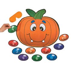 a hand is holding an orange pumpkin with numbers around it