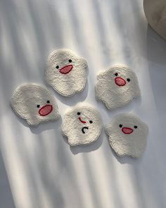 four little felt polar bears sitting on top of a white sheet with red nose noses