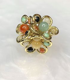 A whimsical vintage natural jade and 14k yellow gold ring. Featuring a unique cluster of 3 multi colored jade flowers joined together with exceptional branch like detailed metalwork which elevates the bouquet high above the hand. Jade has always been known to represent good luck and good fortune, symbolizing balance, harmony and protection. *Approximate ring weight: 14.68 grams *Ring size: US 6 3/4 Vintage Flower-shaped Multi-stone Jewelry, Unique Cluster Multi-stone Rings, Luxury Yellow Gold Cluster Ring, Unique Multi-stone Cluster Ring Gift, Unique Multi-stone Cluster Jewelry, Unique Green Flower Ring, Unique Multicolor Rings With Natural Stones, Jade Rings For Women, Antique Emerald Ring