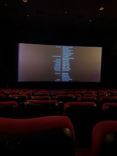 an empty theater with rows of seats and a large screen