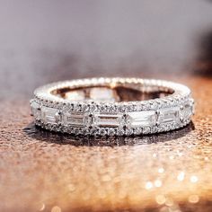 a wedding band with baguettes and diamonds on a shiny surface in front of the camera