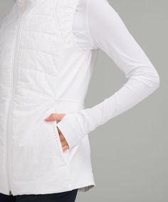 a woman is wearing a white jacket and has her hands on her hip as she stands with her back to the camera