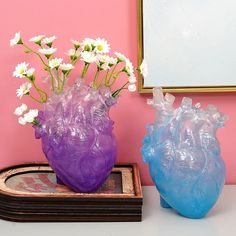 there are two vases with flowers in them on the table next to a mirror