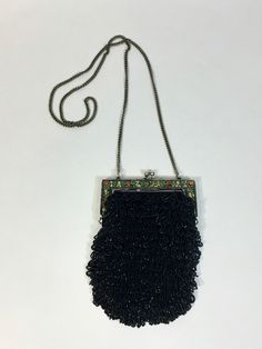 "The perfect addition to your Flapper ensemble or antique purse collection... This gorgeous bag has black fabric main component, decorated with looped fringes of jet black glass faceted beads -giving it a subtle glittery effect. The frame is hand-pounded metal with a lovely floral motif that has been hand-painted with vivid red and green, plus creamy yellow. I really was initially attracted to this bag because of the contrast between subtle black glisten and the bright, juicy colors on the antiqued silver metal. Clasp is kiss lock style and holds shut beautifully. A sturdy, 23\" drop linked chain serves as a long shoulder strap. I should mention that there is quite a bit of weight to this little devil! Condition is excellent, near mint with some overall signs of age, such as light patina t Black Victorian Bag For Vintage Events, Victorian Style Black Bag For Vintage Events, Victorian Black Rectangular Bag, Formal Rectangular Evening Bag With Fringe, Beaded Fringe Evening Bag, Antique Black Evening Bags, Rectangular Beaded Fringe Evening Bag, Rectangular Evening Bag With Fringe, Vintage Black Beaded Evening Bag