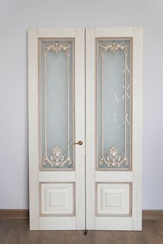 an ornate white door with glass panels and wood flooring in front of a gray wall