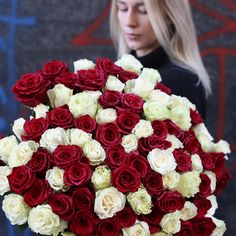 a woman holding a large bouquet of red and white roses