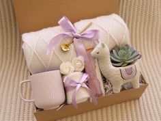 a box filled with baby items on top of a couch next to a cup and blanket