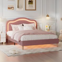 a pink bed with white sheets and pillows in a small room next to pictures on the wall