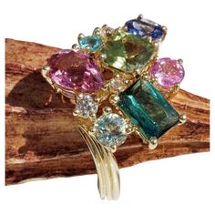 Ring 18 kt Yellow Gold in this ring the best gemstones were combined a potpourri of colors and gemstones pink tourmaline, green-yellow peridot, blue-green indigolite, light green tourmaline, light blue zircon, purple zoisite, total 3. 99 ct, all weights of the single stones engraved in the ring, in between three full cut brilliant-cut diamonds total ca. 0.15 ct, light brown / IF-VVS (flawless-very small inclusions), curved ring shoulders with grooved surface, ca. 20 x 18 x 6 mm, weight ca. 6.2 grams, RW 15.2 mm (can be changed), mint condition, inspired by flowers, a lot of colorful gemstones united in one ring, not often seen, great manufacturing with 18 kt Yellow Gold and Diamonds, handcrafted, very special kind of jewelery by schmuckzicke Luxury Multi-stone Unique Rings, Luxury Gold Gemstones With Accent Stones, Luxury Gold Multi-stone Crystal Ring, Gem Stone Rings, Curved Ring, Colorful Gemstones, Curve Ring, Cluster Rings, Single Stone