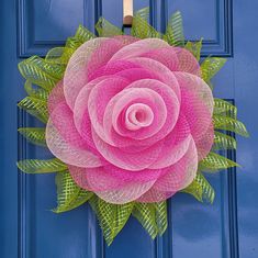 a pink rose on a blue door with green leaves around it and the center is made out of mesh