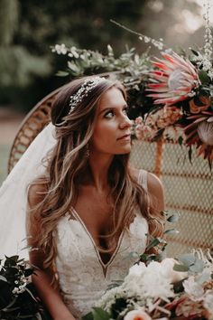 a woman in a wedding dress sitting on a wicker chair with flowers and greenery