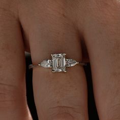 a woman's hand with a diamond ring on top of her finger and an engagement band