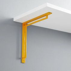 a yellow shelf is hanging on the wall next to a gray wall with white trim