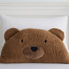 a brown teddy bear pillow sitting on top of a bed