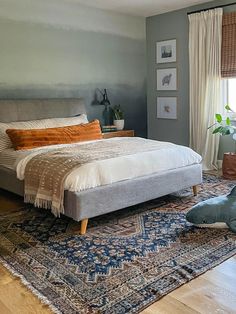 a large bed sitting on top of a wooden floor next to a blue and white rug