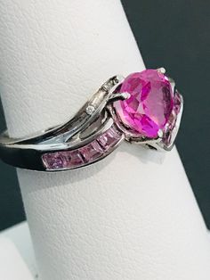 This striking heart shape pink cubic zirconia ring is handmade in sterling silver and is complete with princess cut light powder pink cubic zirconias and two natural white diamond accents. The vibrancy of the center stone will make your mouth water! The design was meticulously thought out as it includes two hearts on each side of the ring in filigree metal work. Can be sized up or down for an additional charge. Feel free to contact us with any questions you may have. Pink Diamond Cut Diamond Ring, Pink Sapphire Ring Fine Jewelry, Elegant Pink Cubic Zirconia Heart Ring, Fine Jewelry Pink Ring With Center Stone, Pink Fine Jewelry Ring With Center Stone, Pink Brilliant Cut Sapphire Ring In Fine Jewelry Style, Pink Brilliant Cut Sapphire Ring Fine Jewelry, Pink Cubic Zirconia Fine Jewelry Ring, Pink Diamond Accented Promise Rings